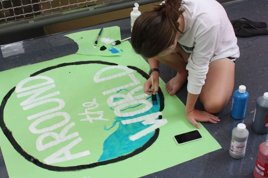 Junior Alyssa Day paints “All Around the World” posters.  These posters were made for reveal day Oct. 2 during Falcon Time. “We liked the theme because we thought it would be fun to decorate the school like that and represent all the different cultures to represent our homecoming,” said Day. 
