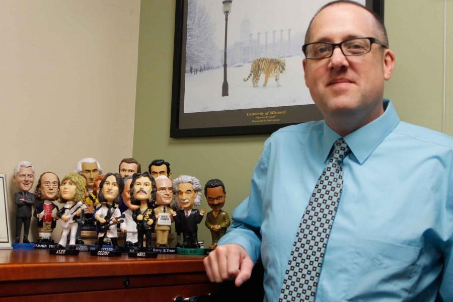 Dr. Chad Brinton poses with his bobblehead collection. 