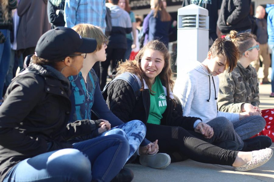 While participating in the walkout on March 14, sophomores Lexi Valdez, Naomi Davis, Maria Engemann, Tanner Sneed and Shayla Crumb-Potmesil sit and hold hands out of respect for the 17 victims of the Parkland, Fla., school shooting. #NationalWalkoutDay was trending globally on Twitter to cover all the walkouts  across the country. “We wanted to sit down to make it better because everyone else was standing and talking and laughing, instead of paying attention to the ones who passed away, said Valdez.
 