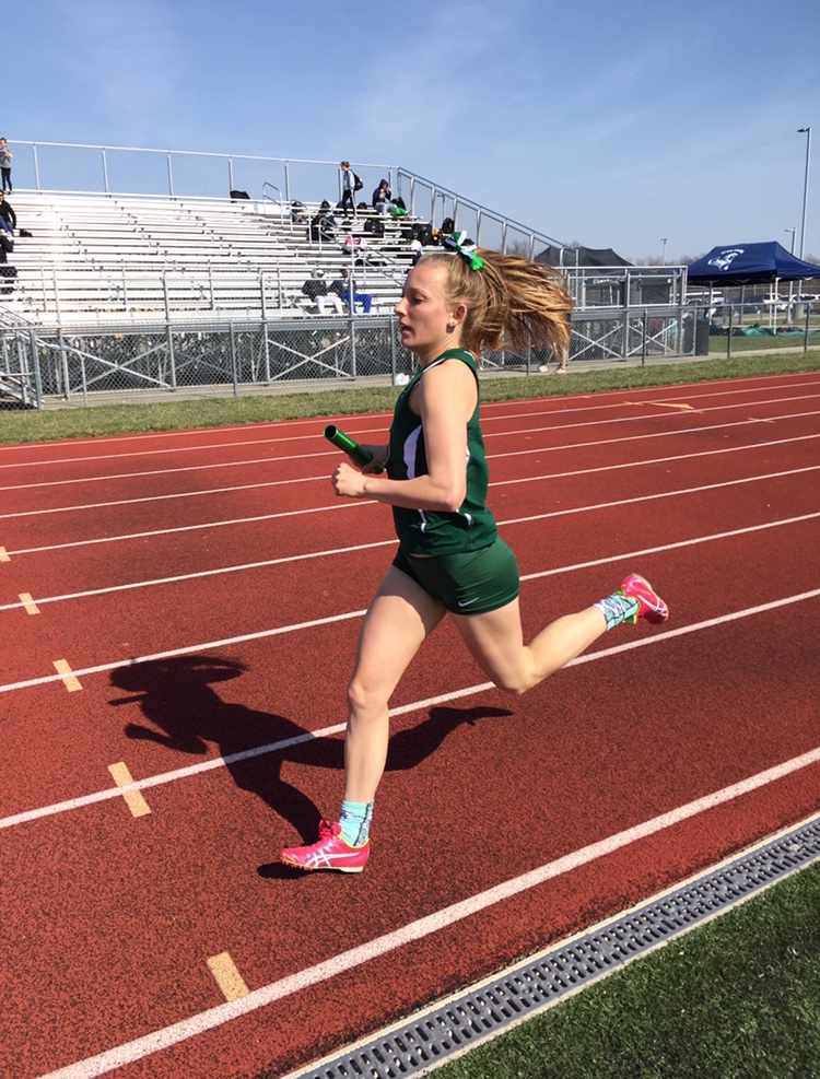 Running the 4x8, sophomore Alex Hamre gets ready to hand the baton off as she runs her last lap where on March 20. Hamre trained hard and ran in every varsity meet in order to reach her goal of breaking the 3200-meter record. “I would do around two hard workouts a week to help me train for it, and I had coach Adair help me by yelling out my splits each 400 to tell me whether I was on pace or not,” said Hamre.