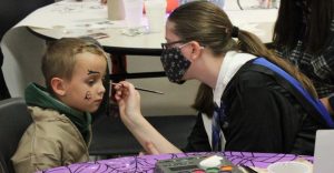 Sophomore Destanie Duncan paints a guests face in the Art Club booth.