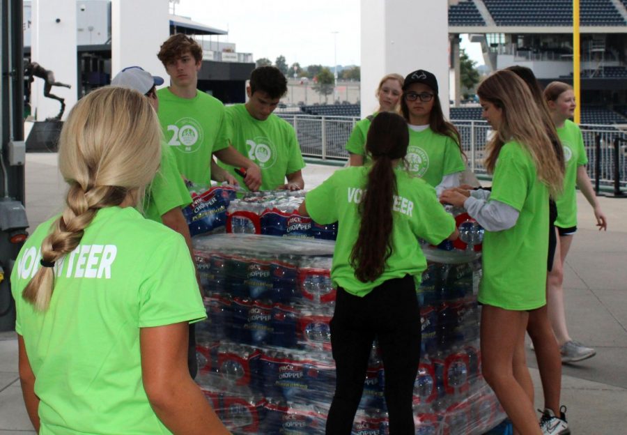 At the ALS walk Oct. 9, NHS members begin unloading water bottle packages from the cart. “My favorite part about the walk was that we were able to come together to help a great cause,” committee leader Ella Bartoski said.