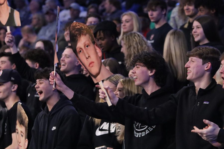 During+the+quarterfinal+game+March+5%2C+seniors+Alex+Gonzalez%2C+Drew+Atkins+and+Jackson+Scott+cheer+for+the+basketball+team+as+Scott+and+Atkins+hold+up+a+Fathead+of+senior+Brogan+Donaldson.+The+Fatheads+were+designed+by+student+section+leader+Tommy+Martin%E2%80%99s+mom.+%E2%80%9CShe+knows+them%2C+and+she%E2%80%99s+always+kind+of+known+them%2C+so+she+created+those+signs+as+a+joke%2C%E2%80%9D+Scott+said.