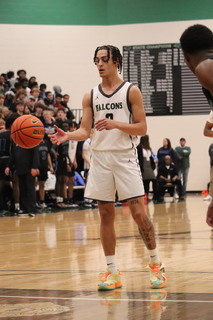 While looking for an open pass Dec. 15 during their home opener against Oak Park, senior Kyan Evans gains possession of the ball. Varsity beat the Northmen 65-36.