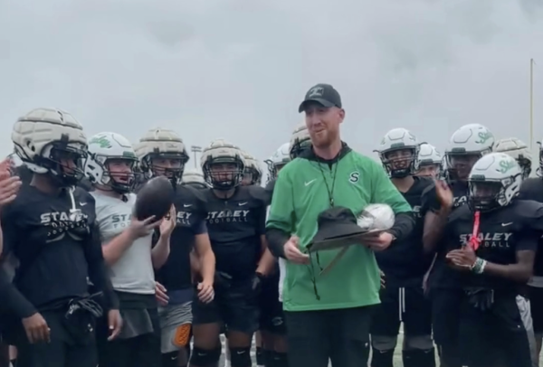 The varsity football team cheers for head coach Drew Hudgins after he was recognized as Chiefs High School Coach of the Week Sept. 23.