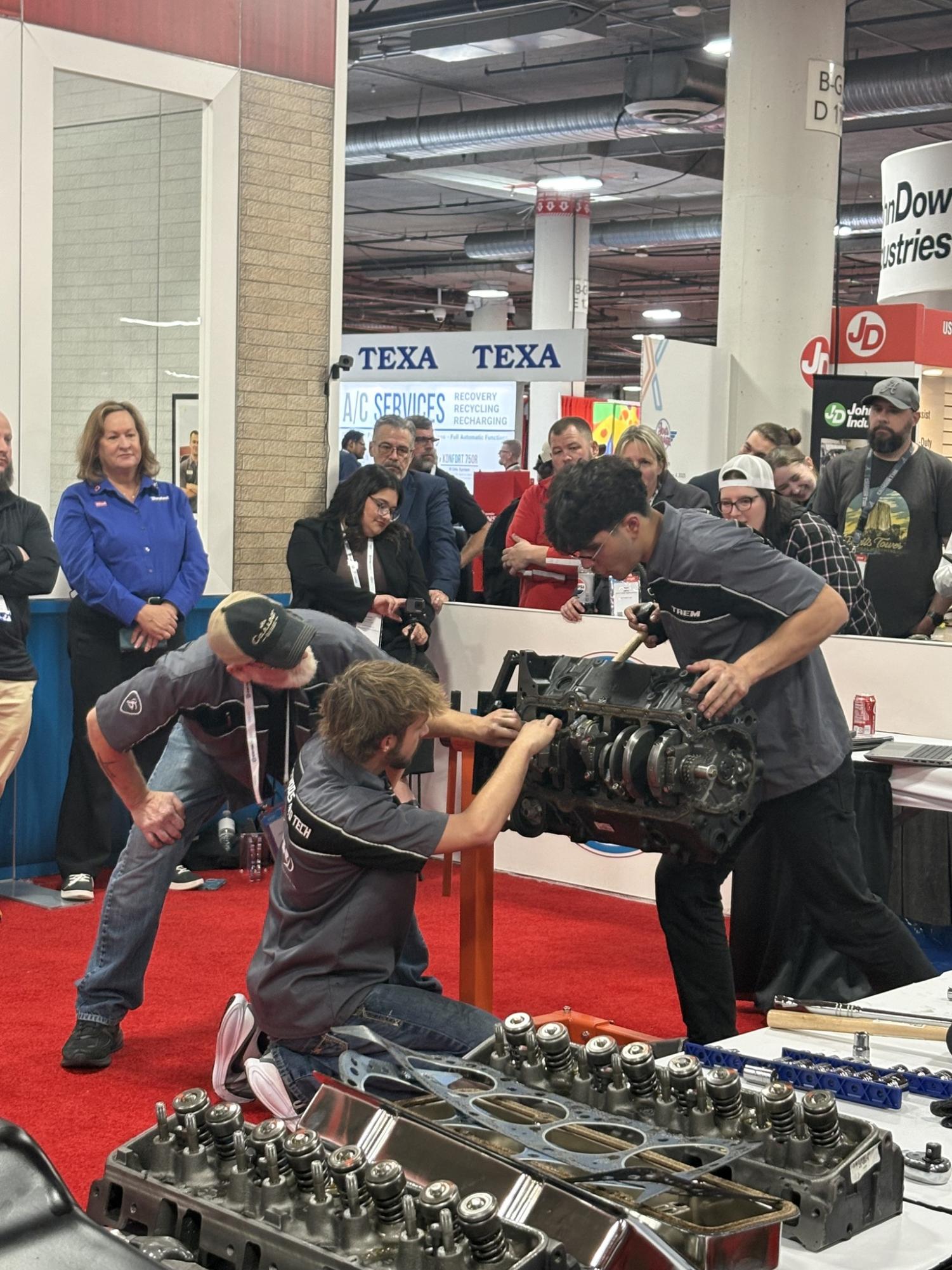 Teacher Jack Stow coaches as Staley junior Adrian Madinger and Oak Park High School student Taem Aljallad work to rebuild the engine.